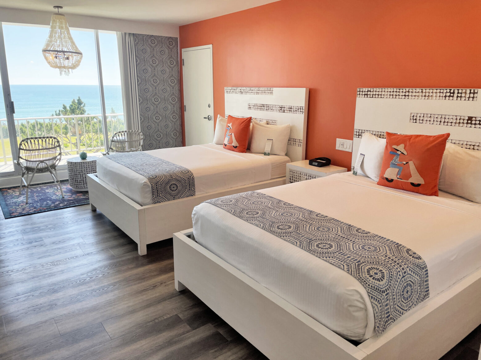 Two queen beds with brightly colored bedding and ocean views.